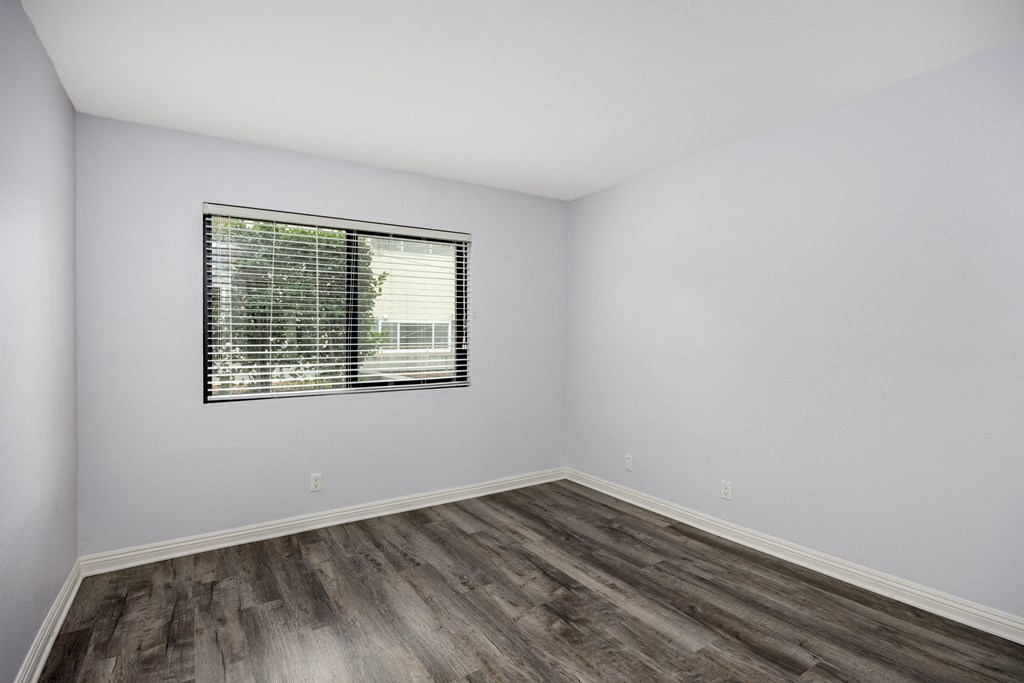 A room with a window and wooden flooring.
