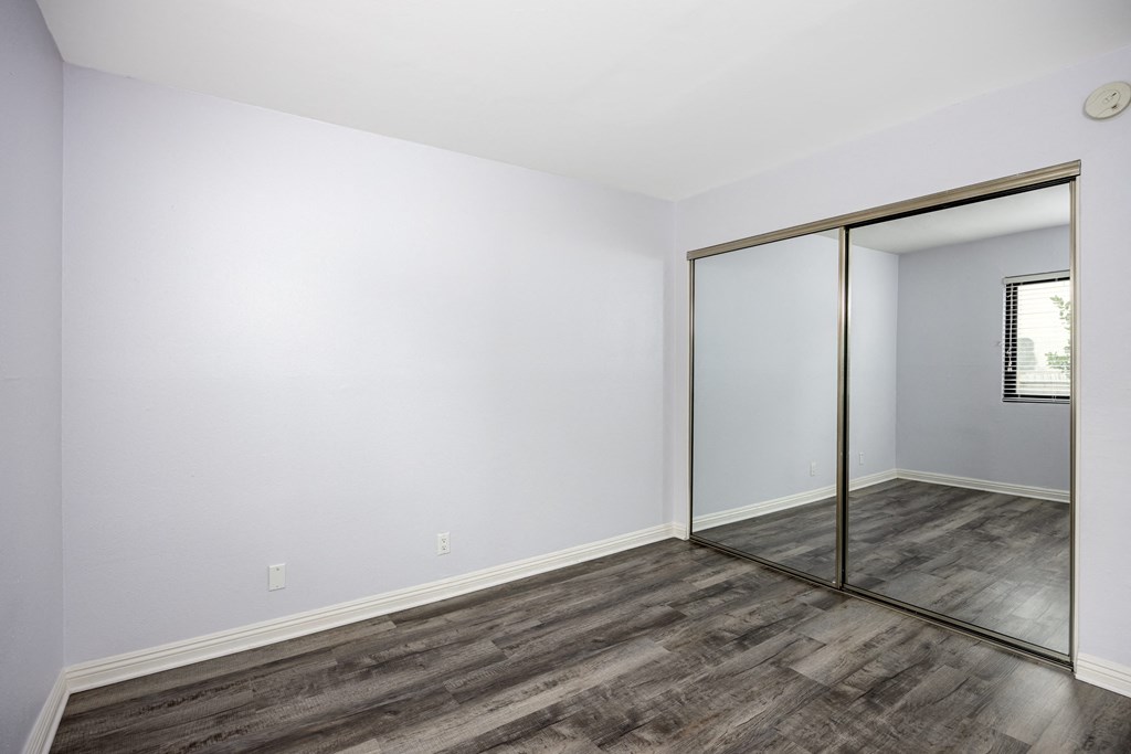 A room with a wooden floor and a mirror on the wall.