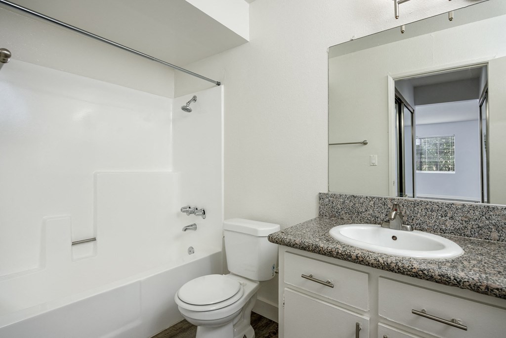 A white toilet sits in a bathroom next to a sink.