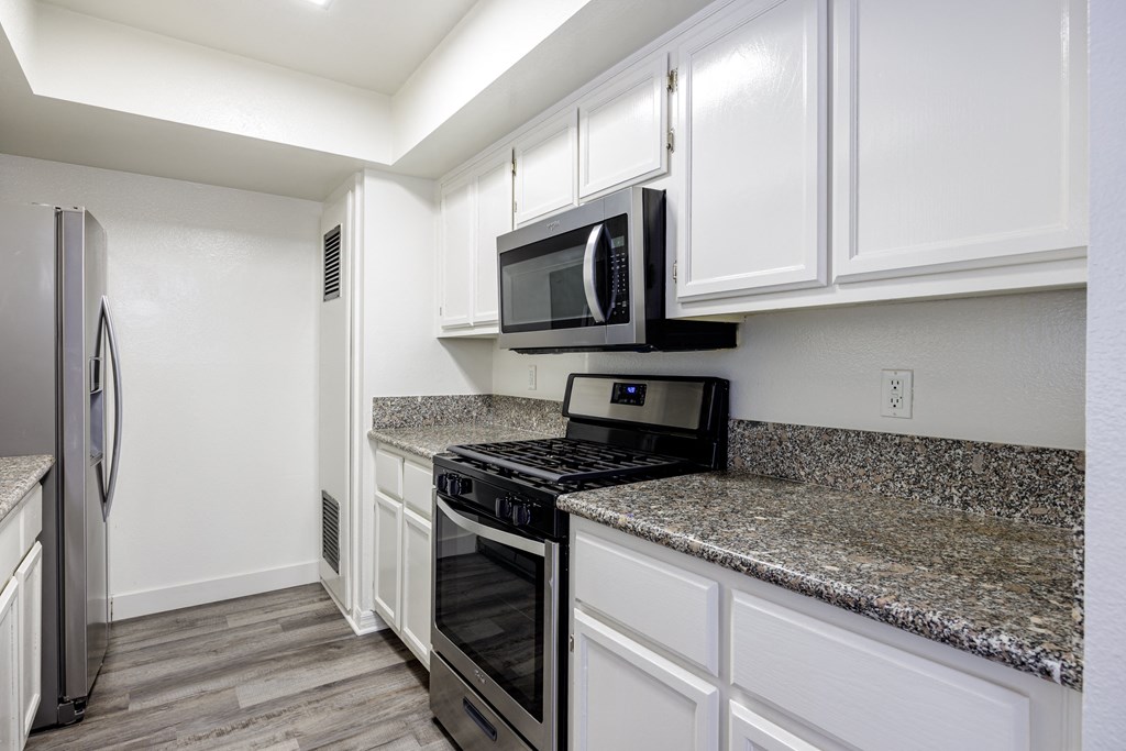 A kitchen with a granite countertop and white cabinets.