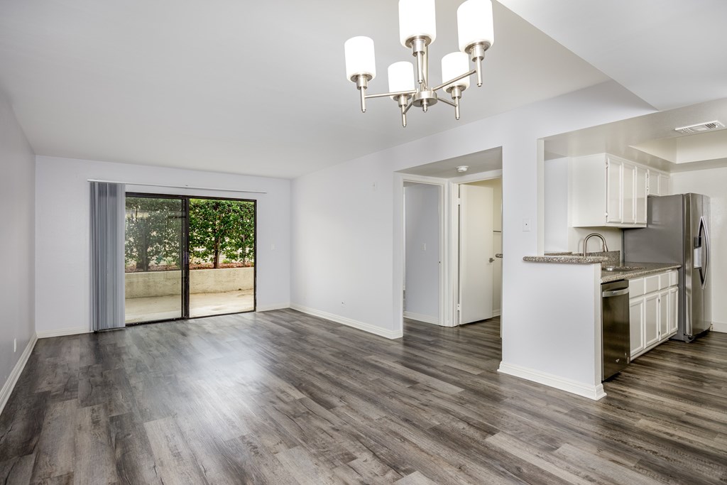 A spacious kitchen and living room with wooden floors and white walls.