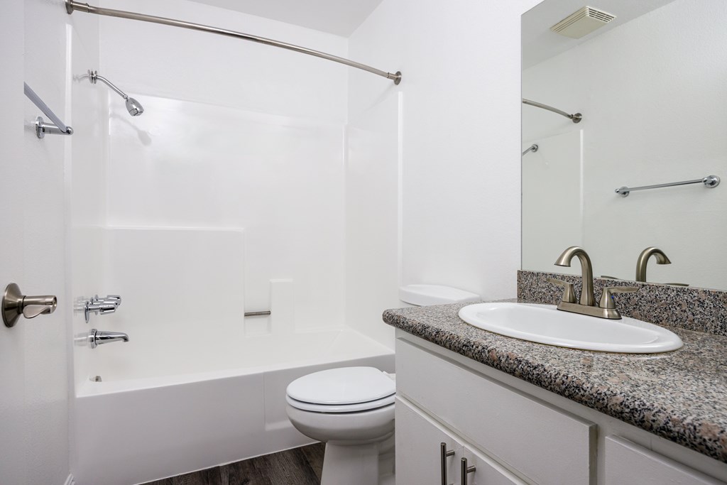 A white bathroom with a toilet, sink, and bathtub.