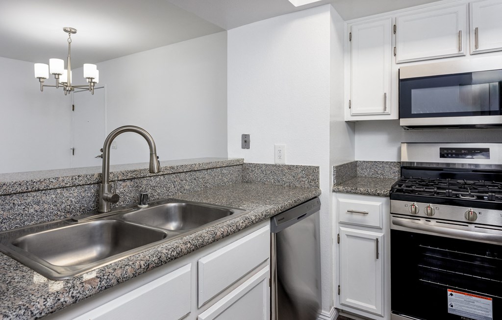 A kitchen with a stainless steel sink and a stove top oven.