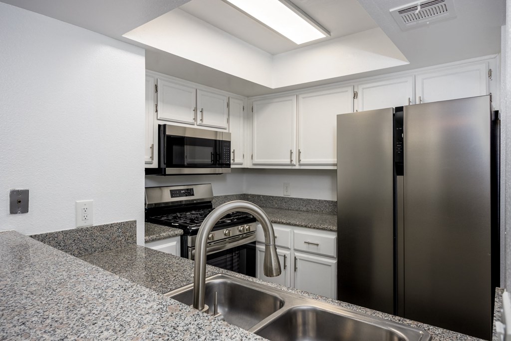 A kitchen with a granite counter top and stainless steel appliances.
