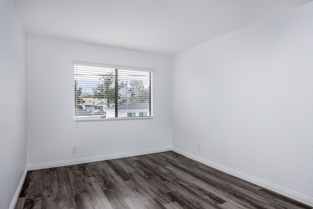 A room with a window and wooden flooring.