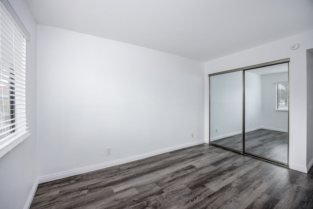 A room with a sliding glass door and wooden flooring.