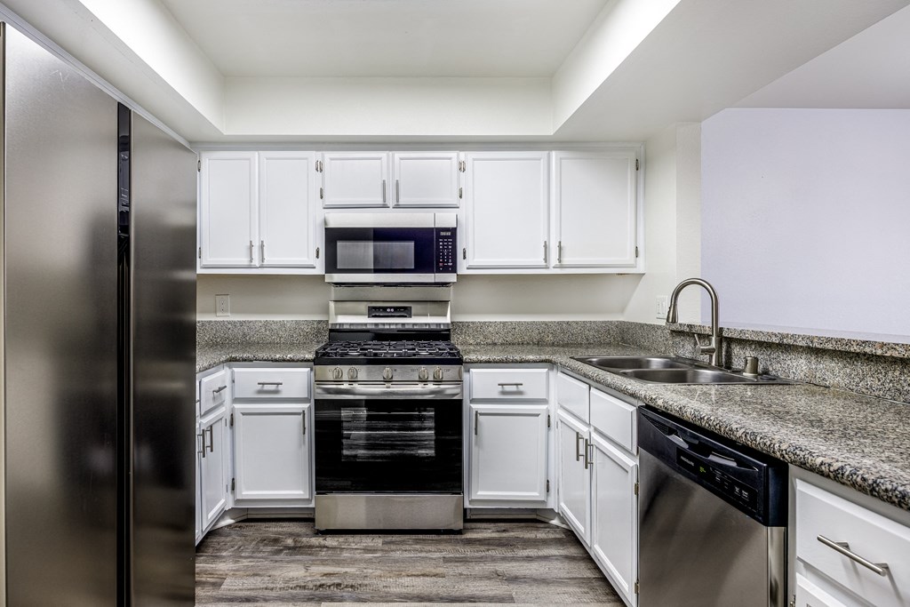 A modern kitchen with white cabinets and stainless steel appliances.