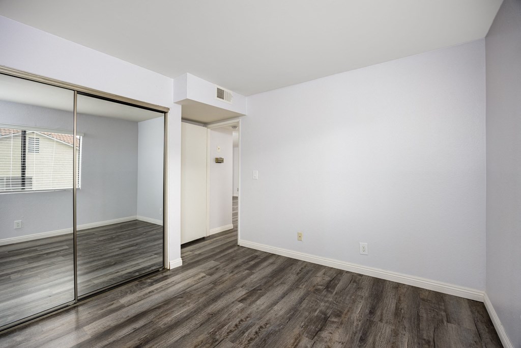 A room with a sliding glass door and wood flooring.