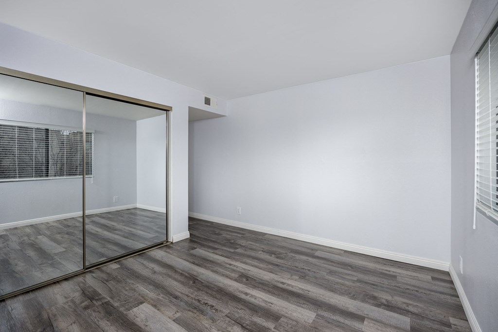 A room with a sliding glass door and wood flooring.