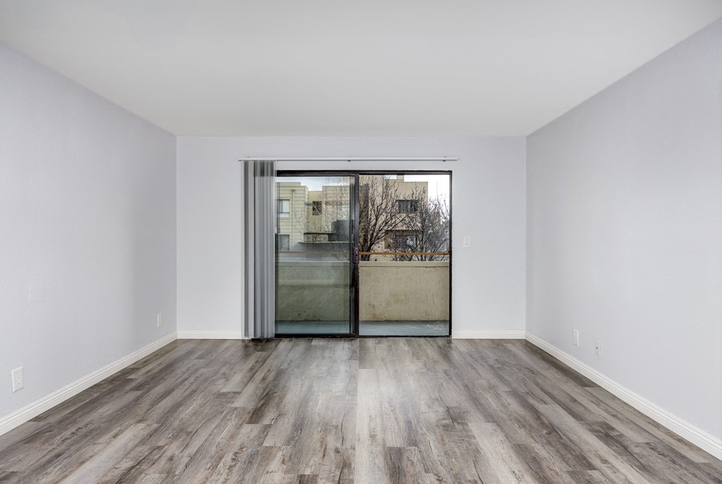 A room with a wooden floor and a sliding glass door.