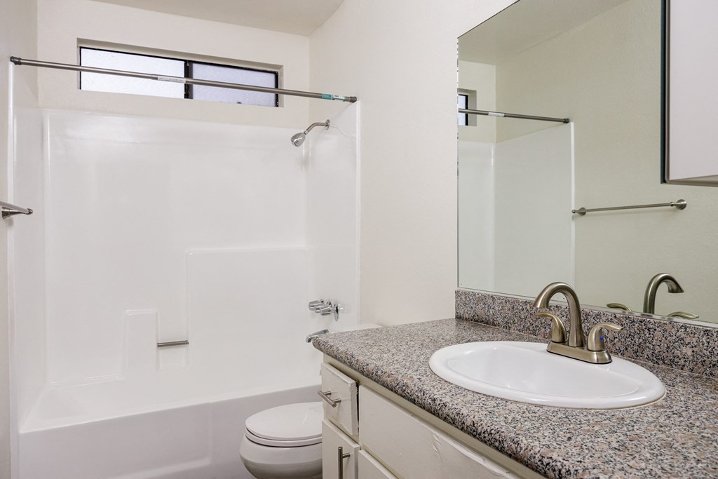 A bathroom with a granite countertop and a white sink.