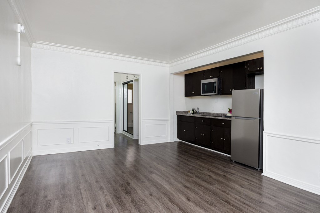 an empty room with white walls and a kitchen with stainless steel appliances