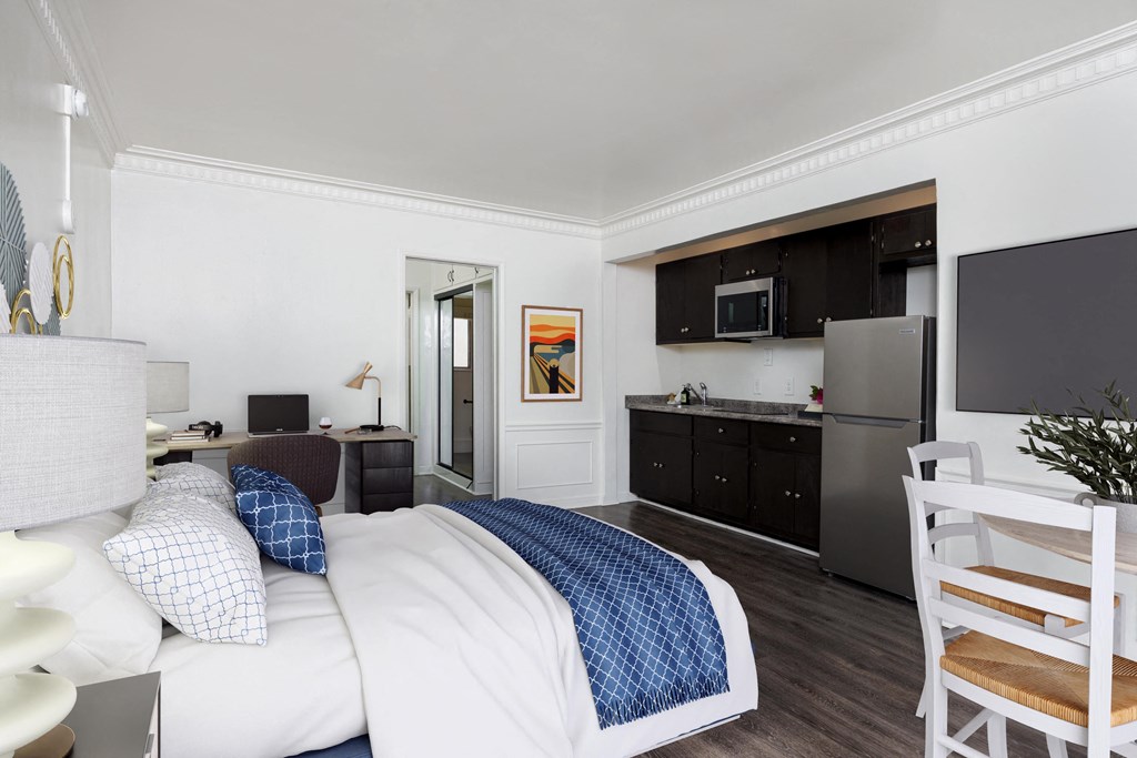 a bedroom with a bed and a kitchen with a refrigerator