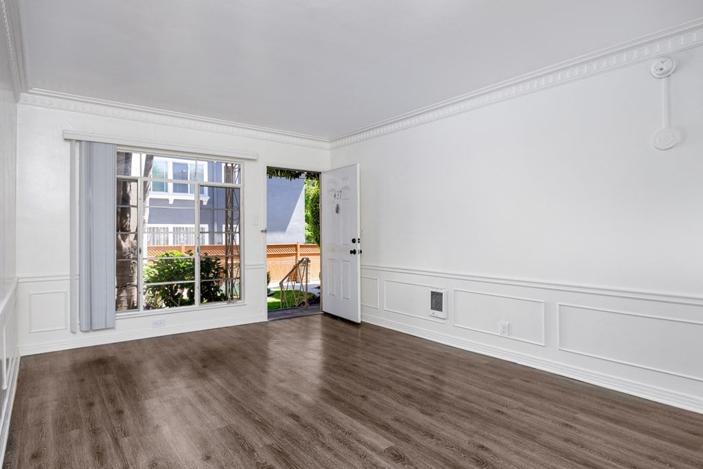 an empty living room with a large window and wood floors