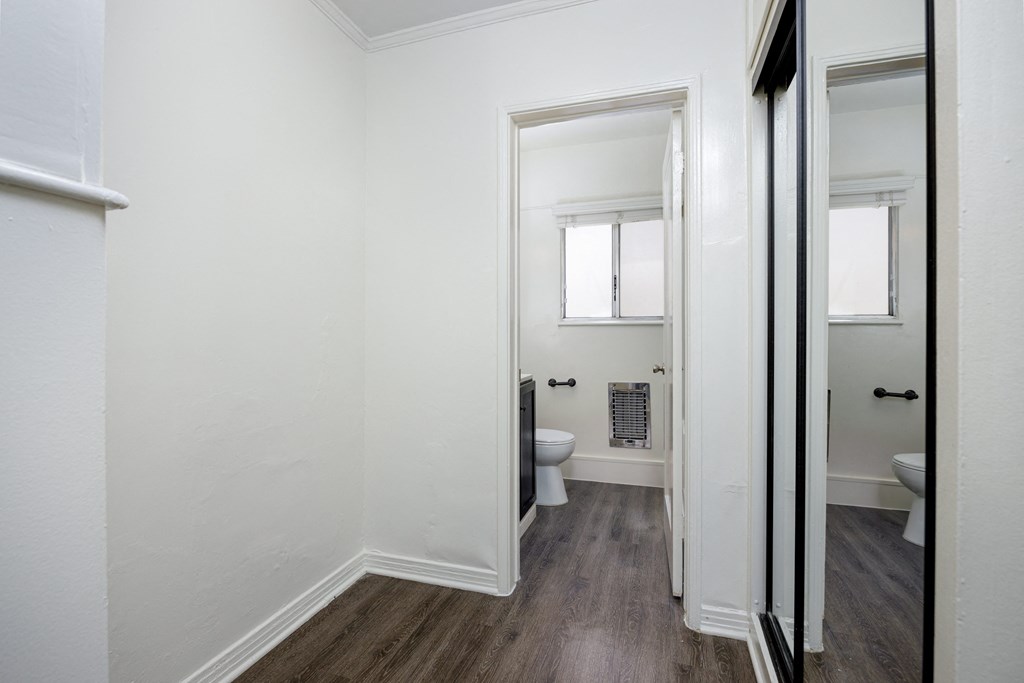 a small bathroom with white walls and wood floors and a toilet