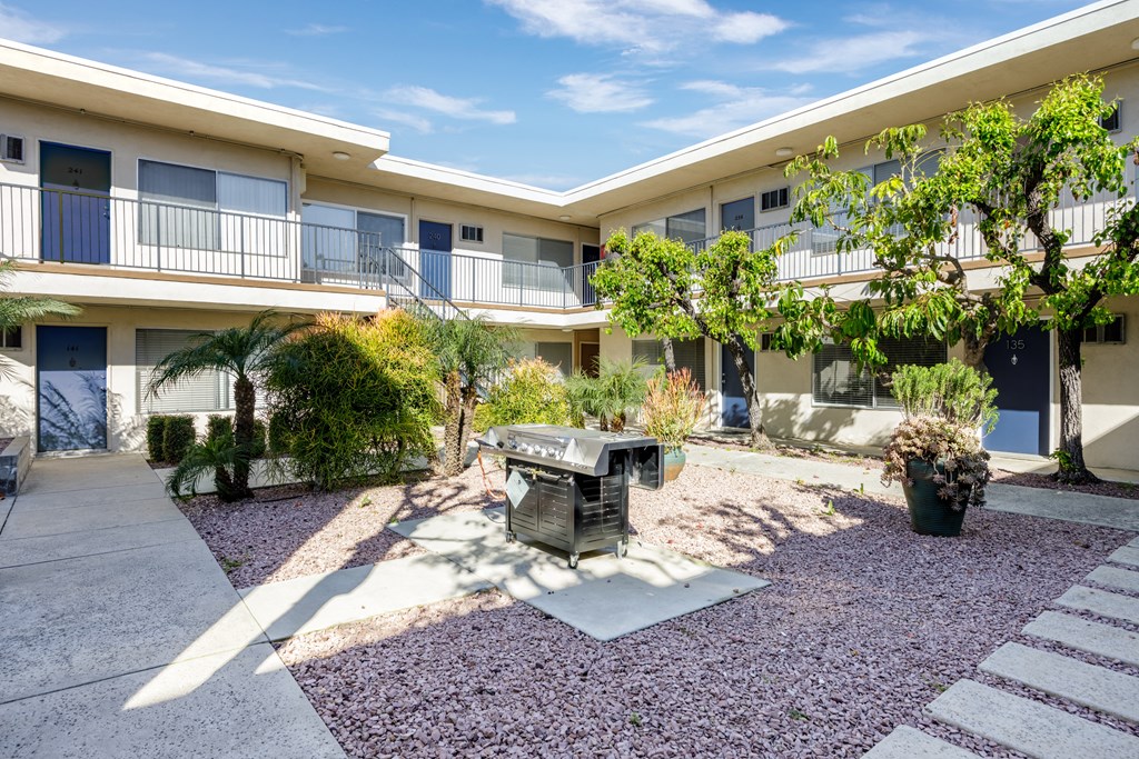 a courtyard with a grill and plants in front of a building
