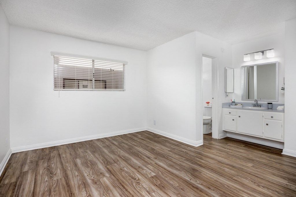 the living room of a renovated apartment with wood flooring and a bathroom