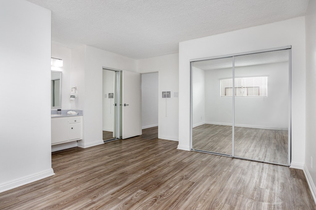 an empty bedroom with a mirrored closet and a bathroom