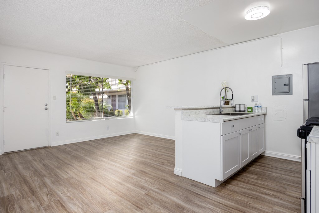 an empty kitchen and living room with white walls and wood floors