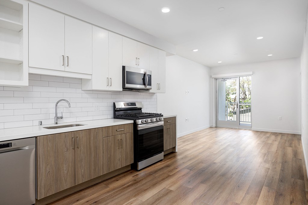 a white kitchen with wooden floors and white cabinets