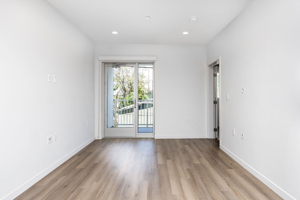 a living room with white walls and a door to a balcony