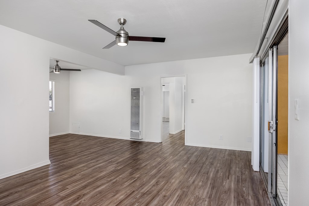 A room with a ceiling fan and wooden flooring.
