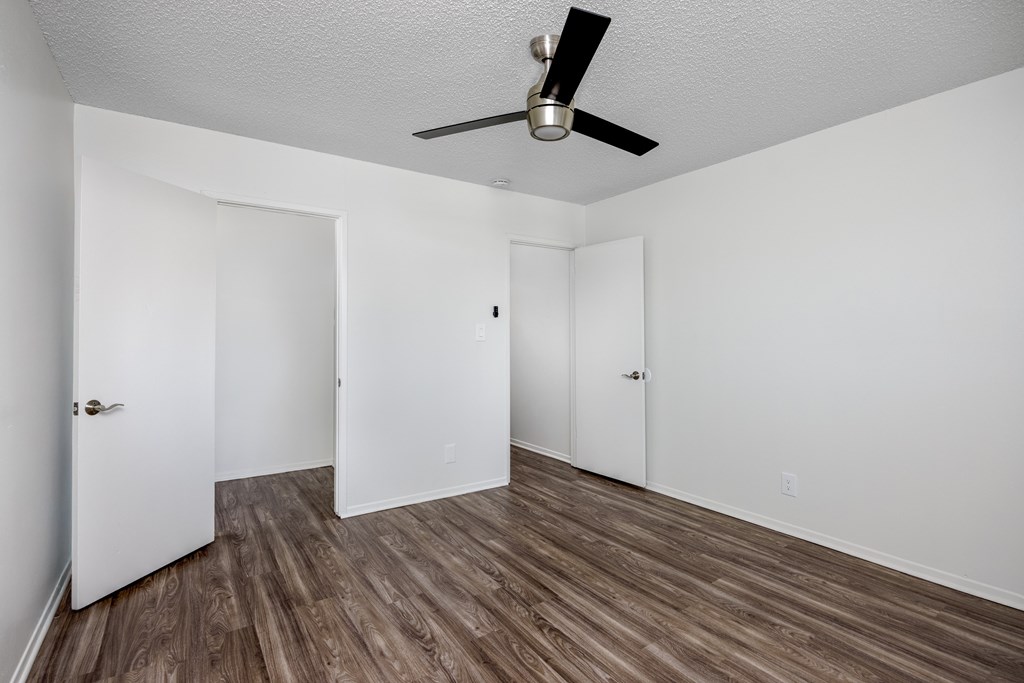 A room with a ceiling fan and wood flooring.