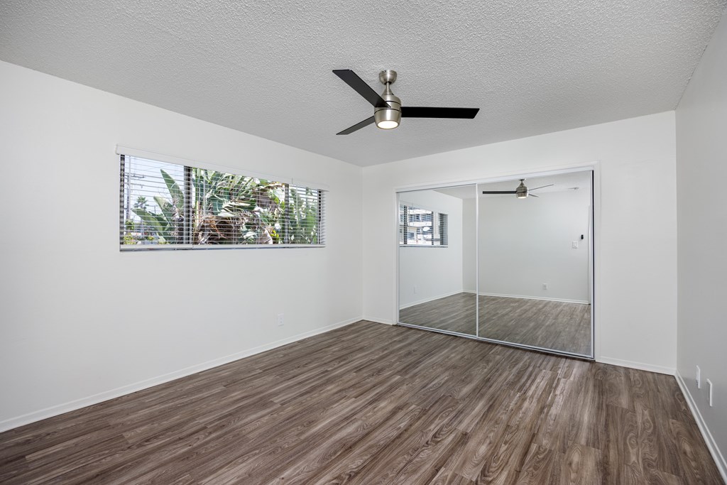 A room with a ceiling fan and wooden flooring.
