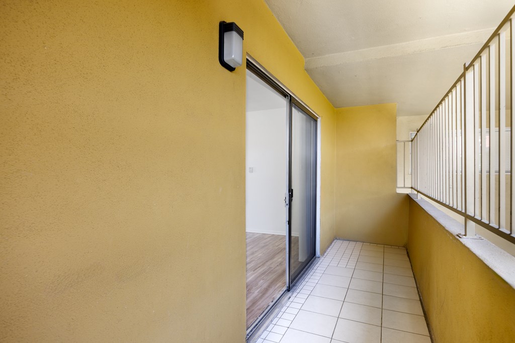 A hallway with a yellow wall and a sliding glass door.