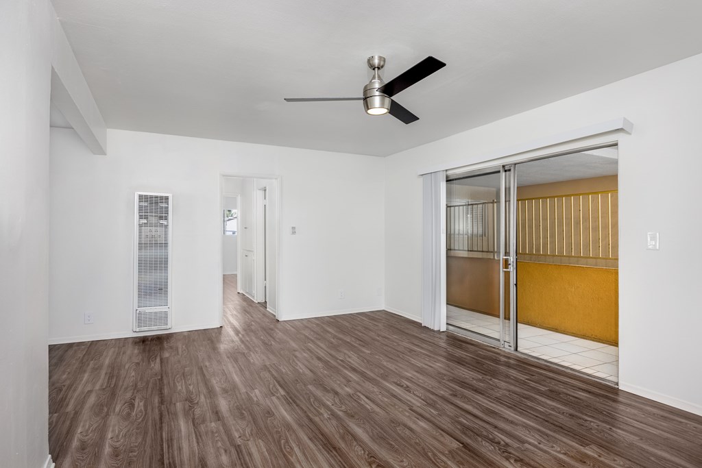 A room with a ceiling fan and sliding glass doors.