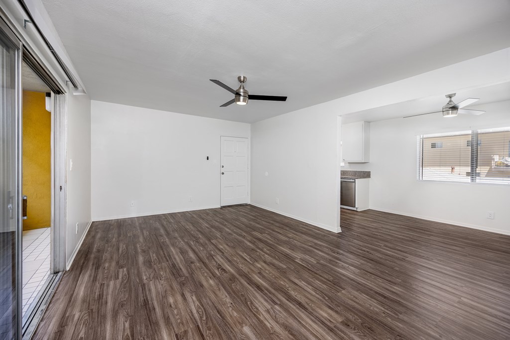 A room with a ceiling fan and wooden flooring.