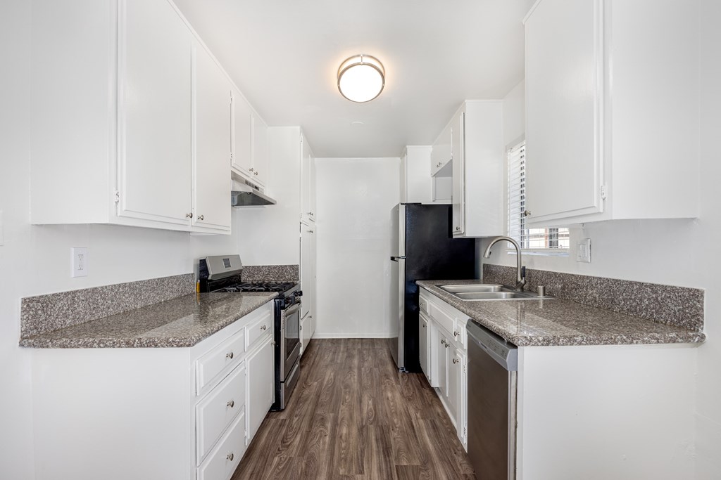A kitchen with white cabinets and a granite countertop.