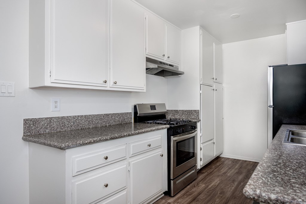 A kitchen with white cabinets and a granite countertop.