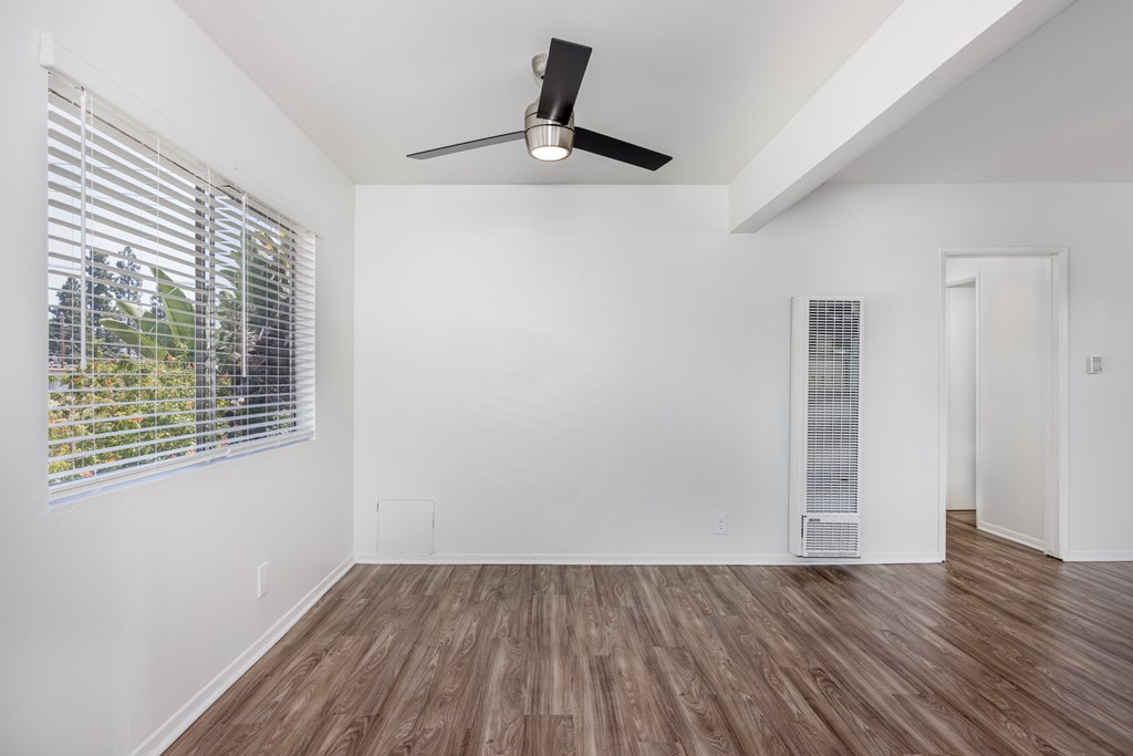 A room with a ceiling fan and wooden flooring.