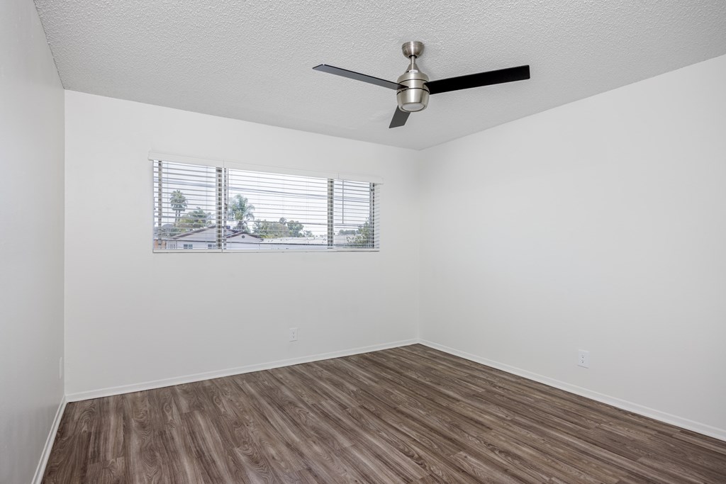 A room with a ceiling fan and a window with blinds.