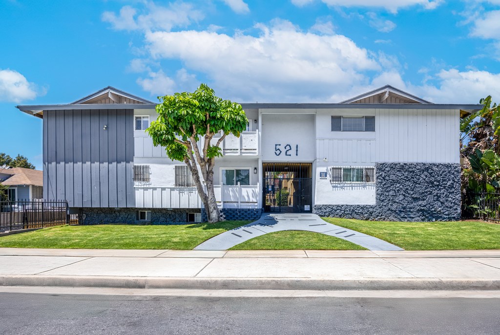 A modern two-story house with a white and grey exterior and a tree in front.