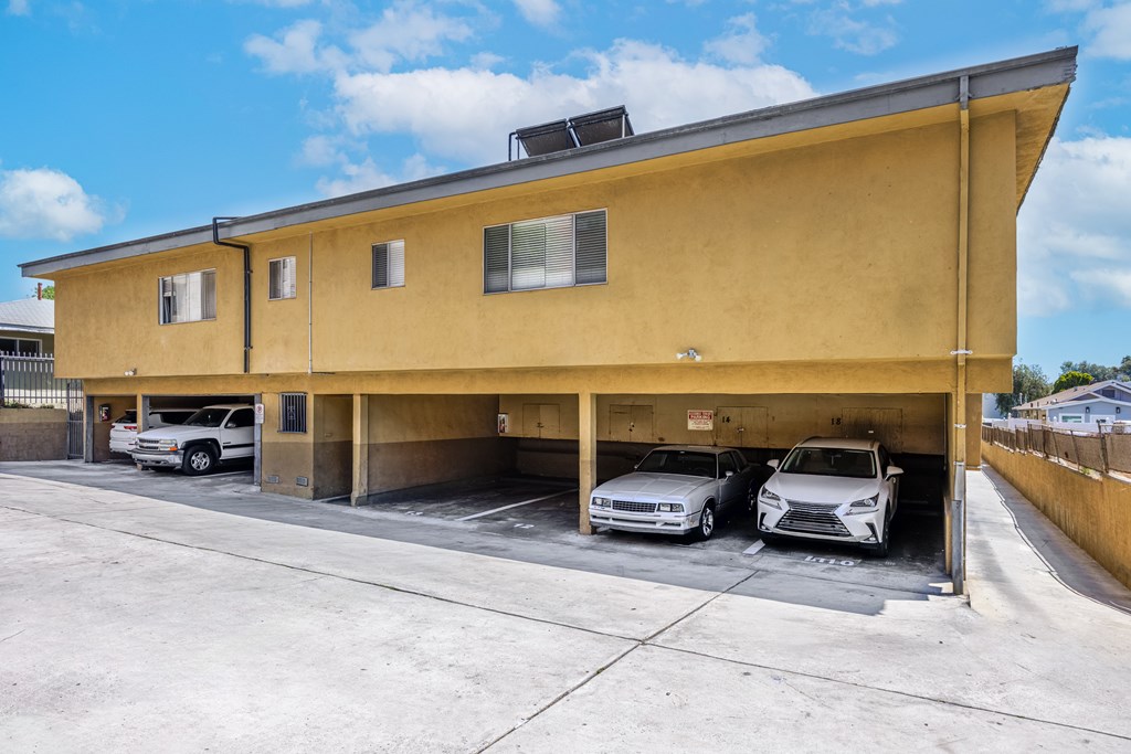 A yellow building with a garage door open and two cars inside.