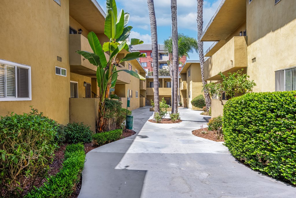 A concrete pathway leads through a row of apartment buildings.