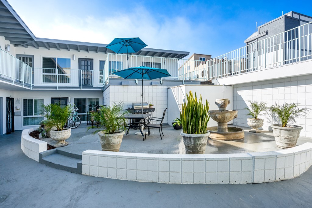 A patio with a fountain and potted plants.