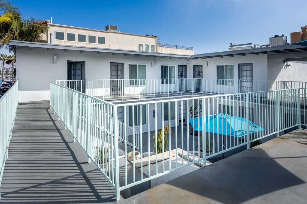 A white building with a blue pool in front.