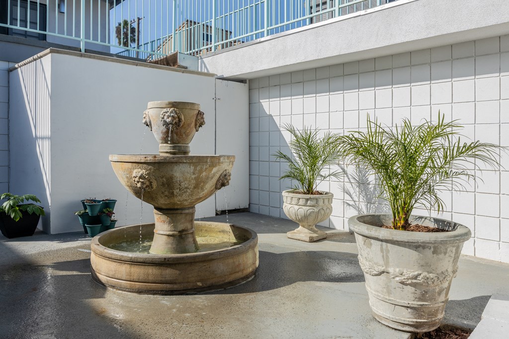 A stone fountain is in the middle of a courtyard.