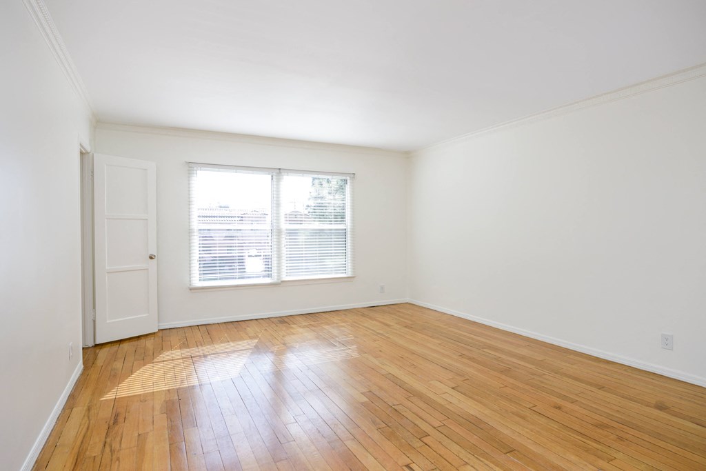 an empty living room with wood floors and a window