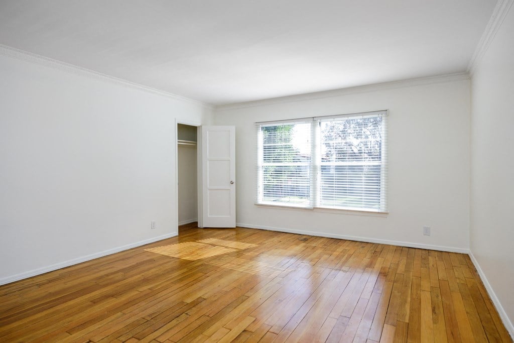 an empty living room with wood floors and a window