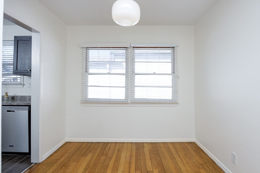 an empty living room with a window and a kitchen
