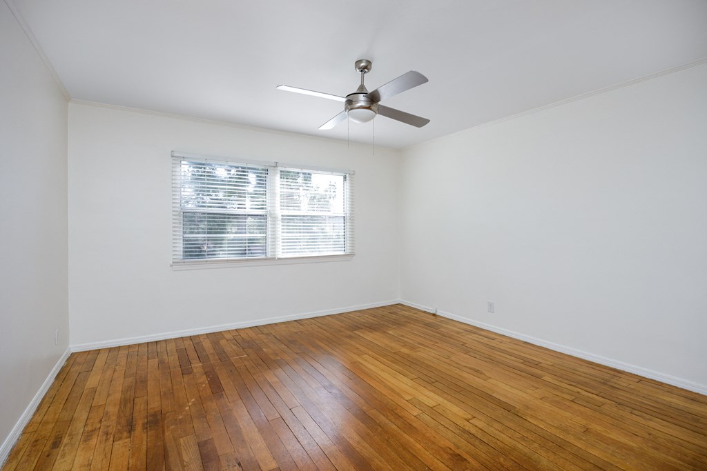 an empty living room with wood floors and a ceiling fan