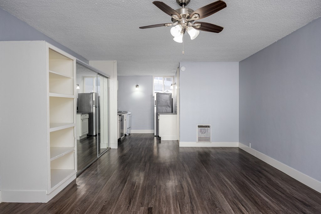 A room with a ceiling fan and wooden flooring.