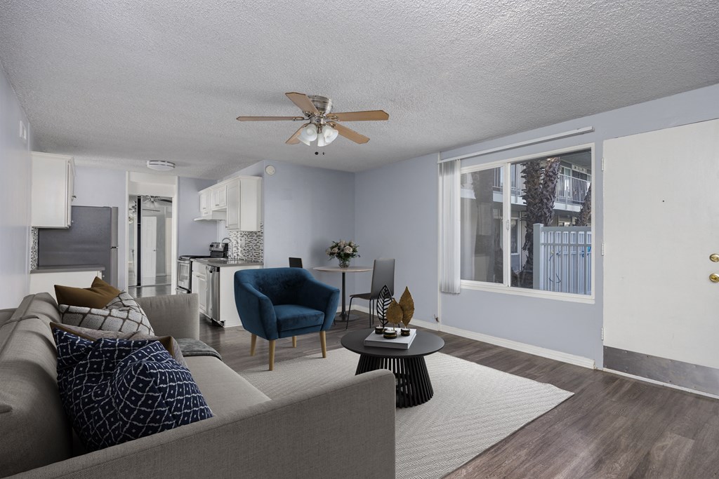 A living room with a grey couch, a blue chair, and a ceiling fan.