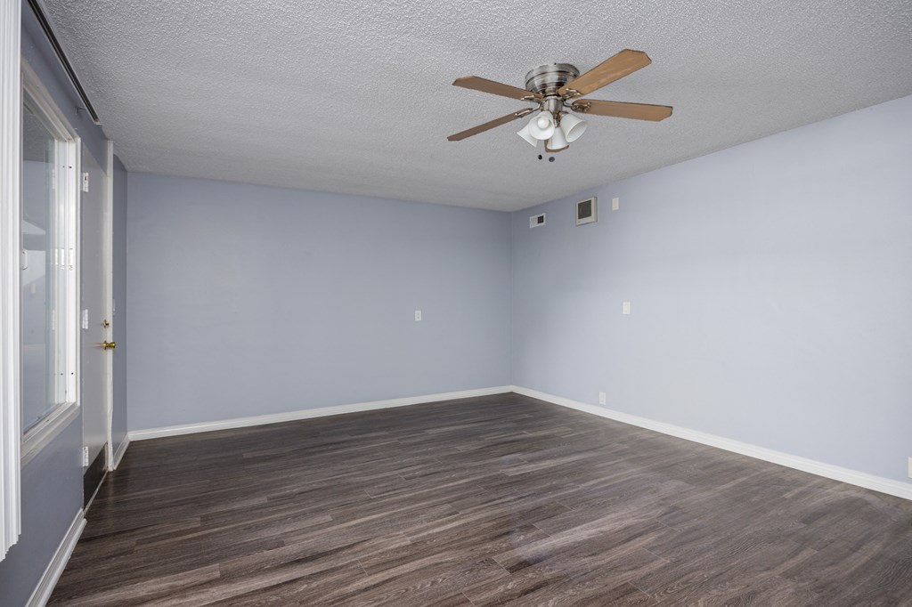 A room with a ceiling fan and wooden flooring.