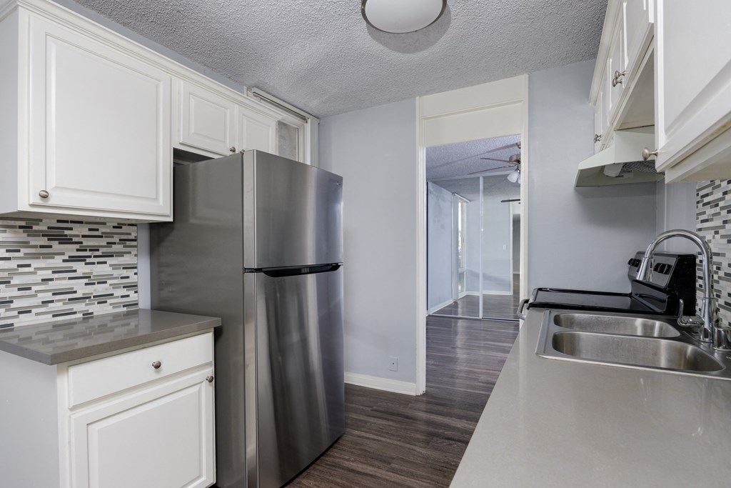 A kitchen with a stainless steel refrigerator and a sink.