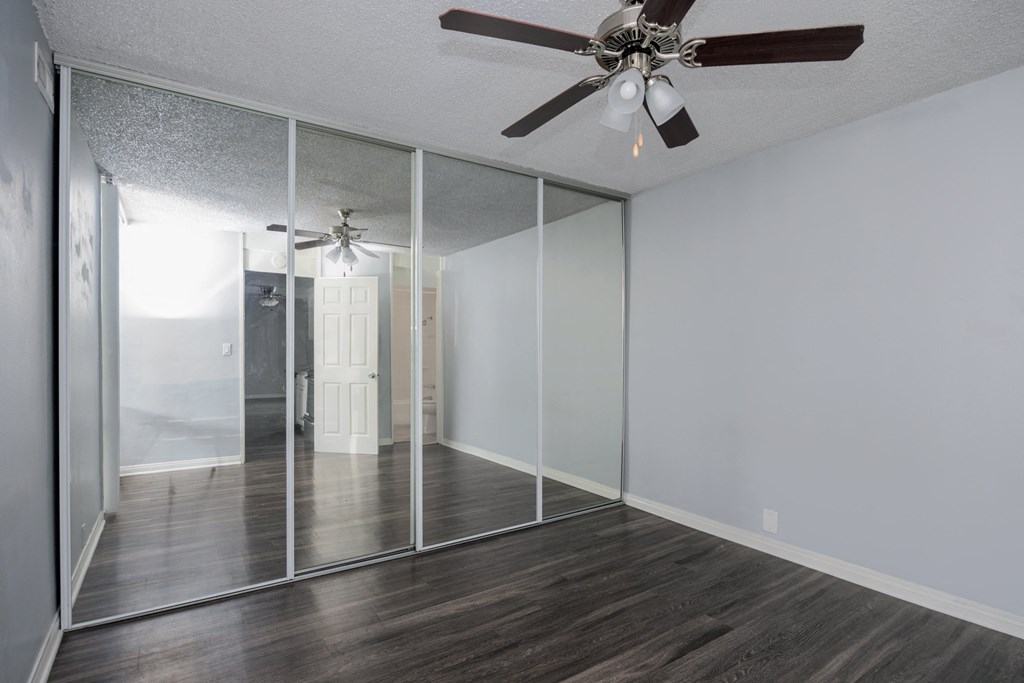 A room with a ceiling fan and sliding glass doors.
